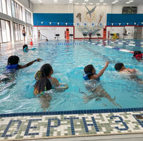 Kids swimming away from the edge of an indoor pool