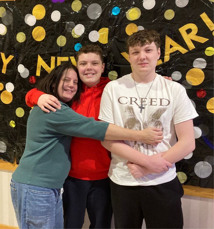 a family hugging in front of a New Year banner