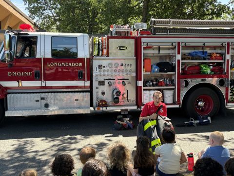 A firefighter talks to a group of children in front of a fire truck